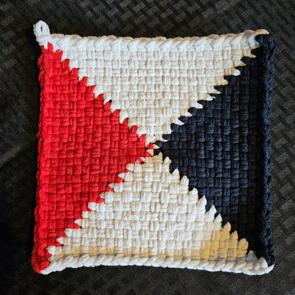 Square woven patch with red, white, and blue geometric pattern on a textured black background