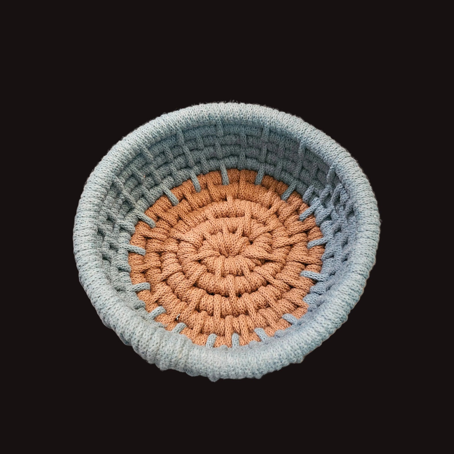 A small round coiled basket with concentric rings of blue and brown