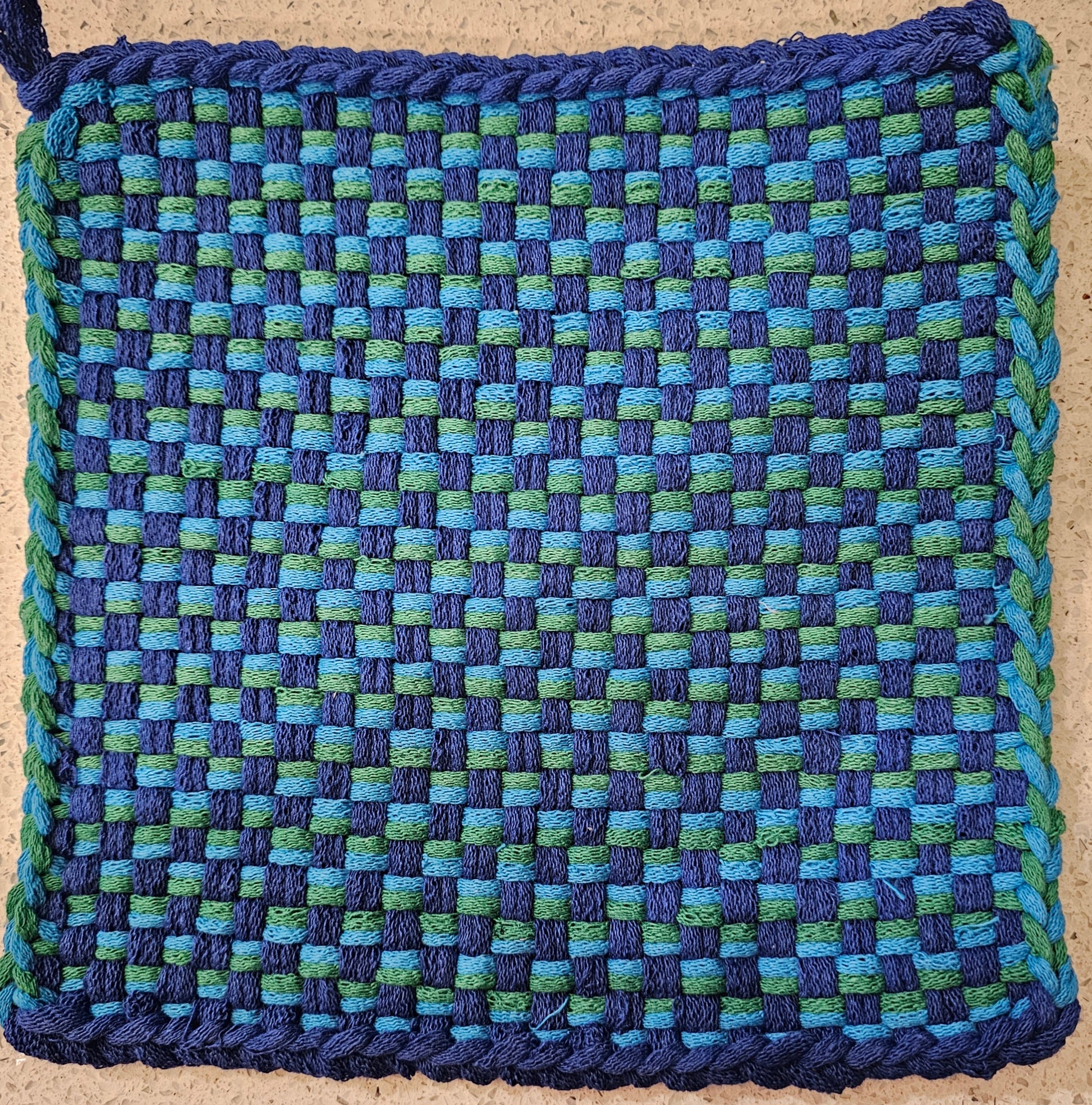 Woven blue and green square on a cardboard background