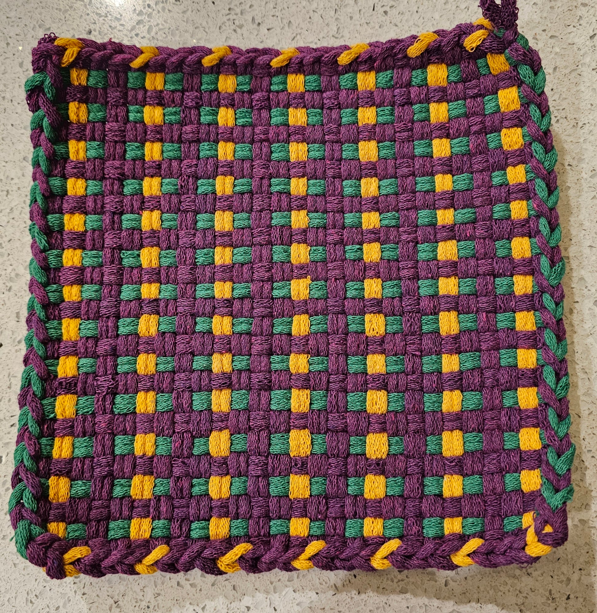 Woven potholder with purple, green, and yellow pattern on a neutral background