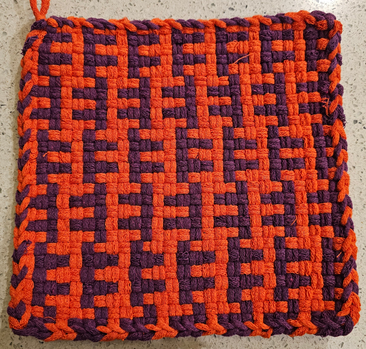 Woven pot holder with orange and purple pattern 