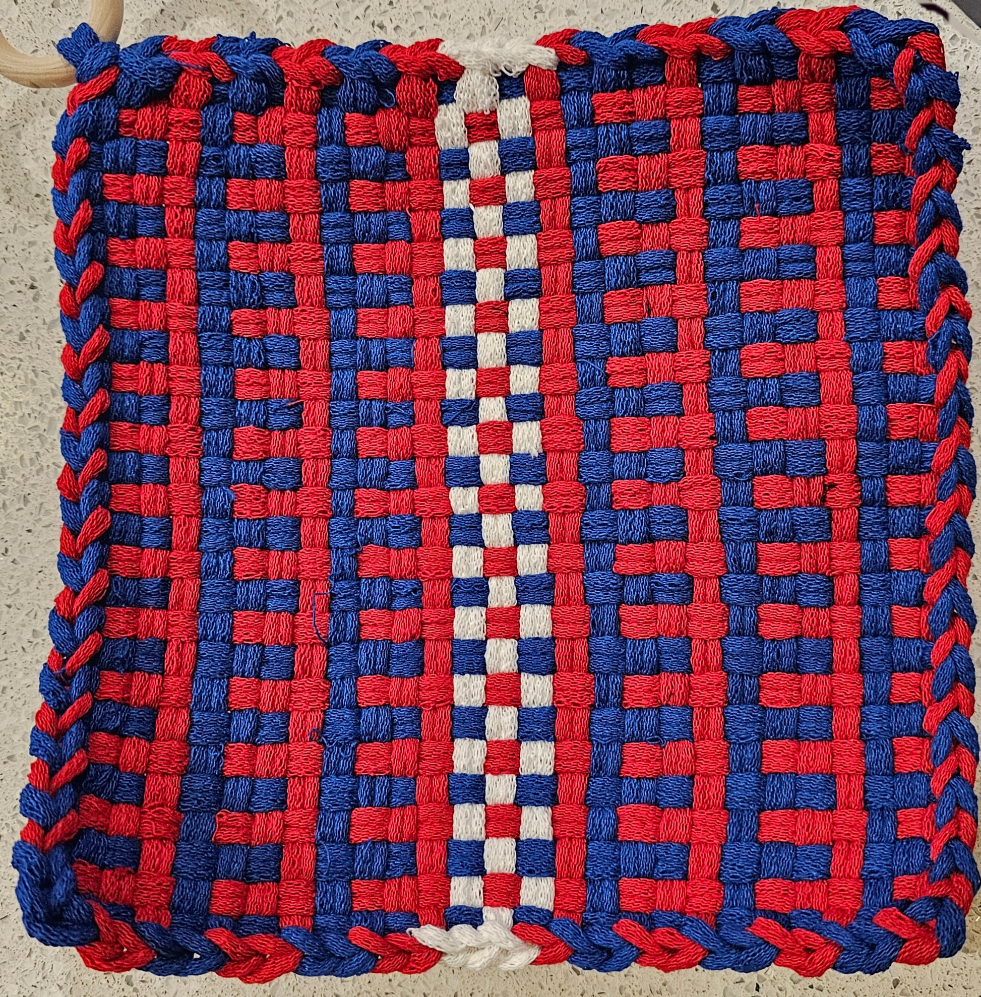 Woven mat with red and blue pattern on a neutral background