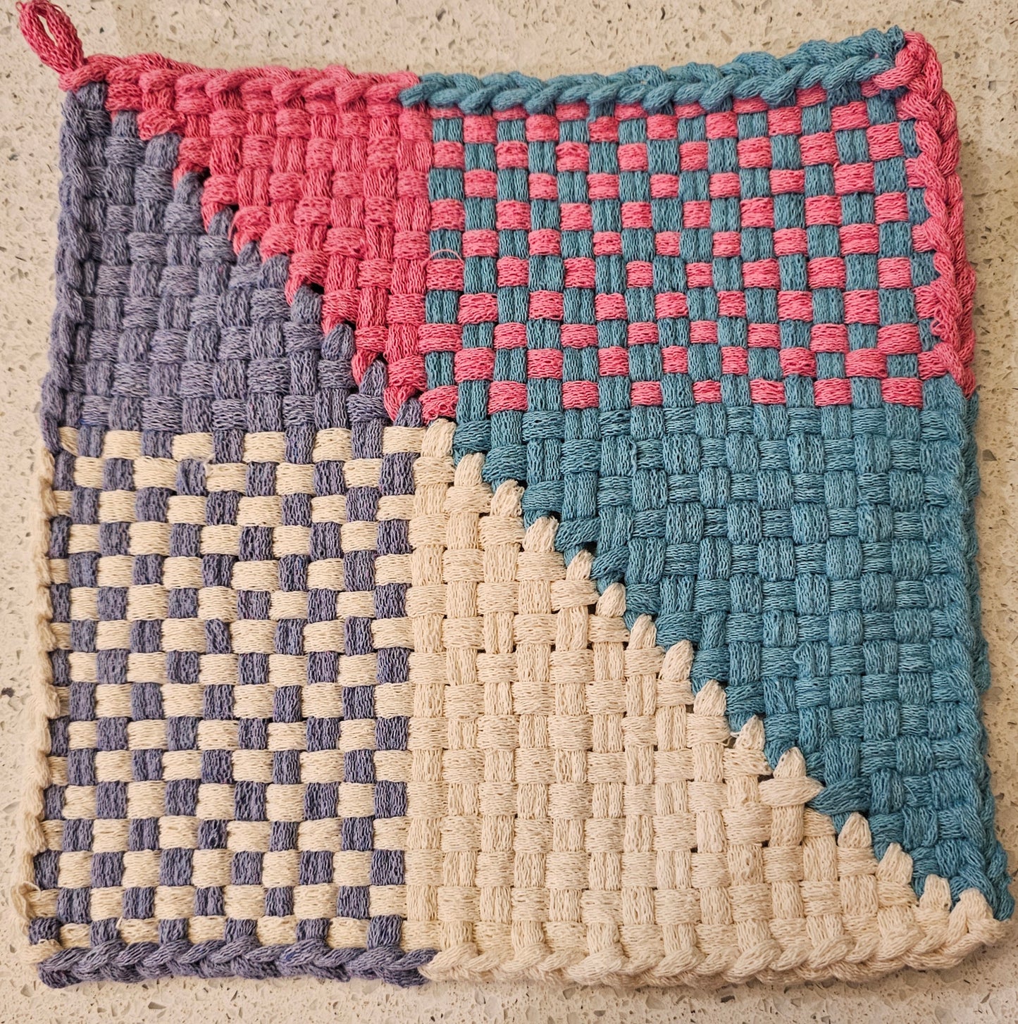 Woven potholder with pink, blue, and cream patterns 