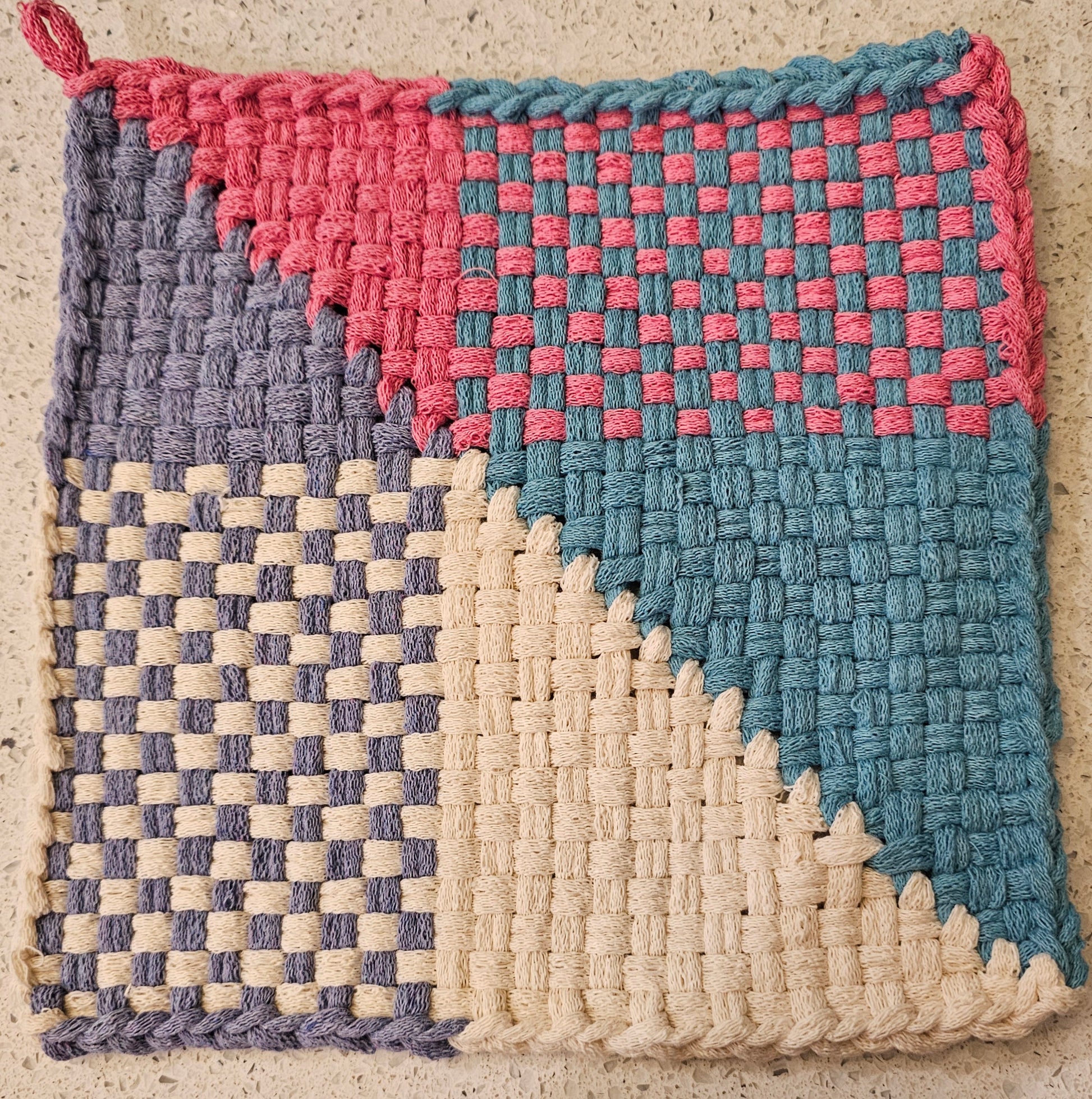 Woven potholder with pink, blue, and cream patterns 
