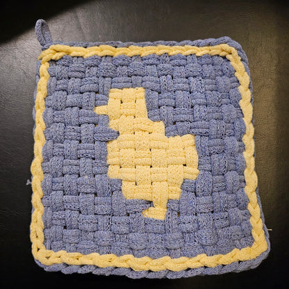 Woven pot holder with blue and yellow pattern on a dark surface