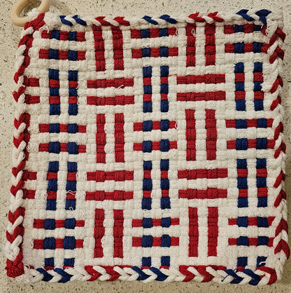 Woven mat with red, white, and blue pattern on a textured surface