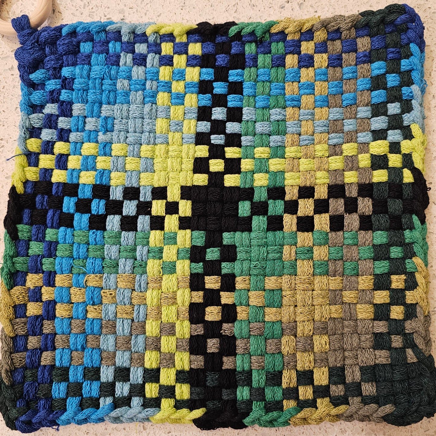 Woven mat with a geometric pattern in various colors on a neutral background