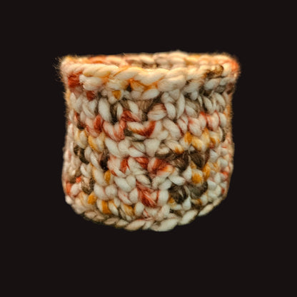 A handmade chunky knit cup in a variegated cream, brown, and rust-orange yarn; perfect for pens and pencils