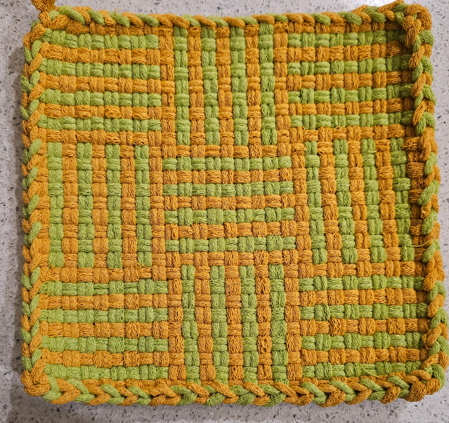 Woven green and orange mat on a textured surface