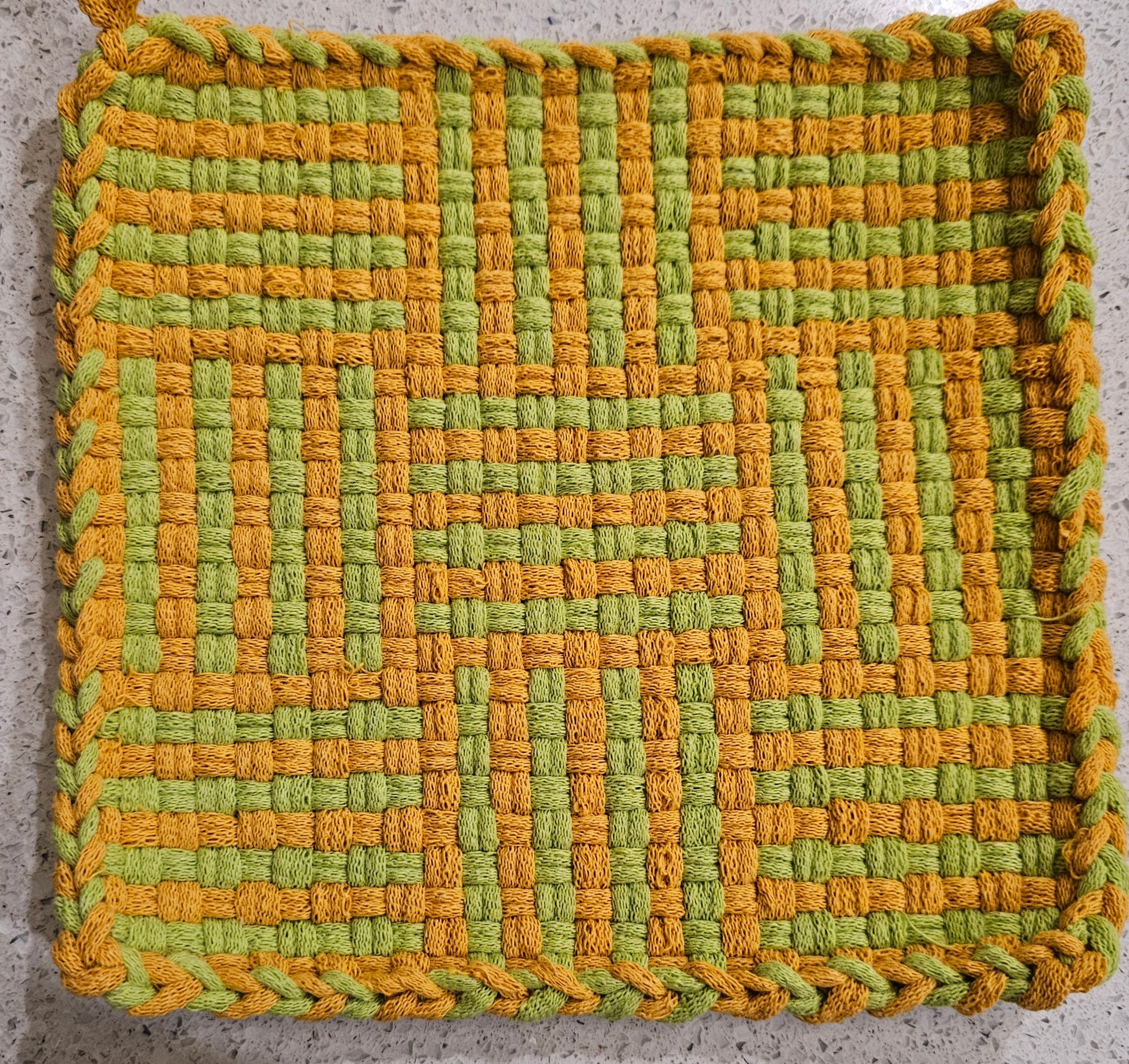 Woven green and orange mat on a textured surface