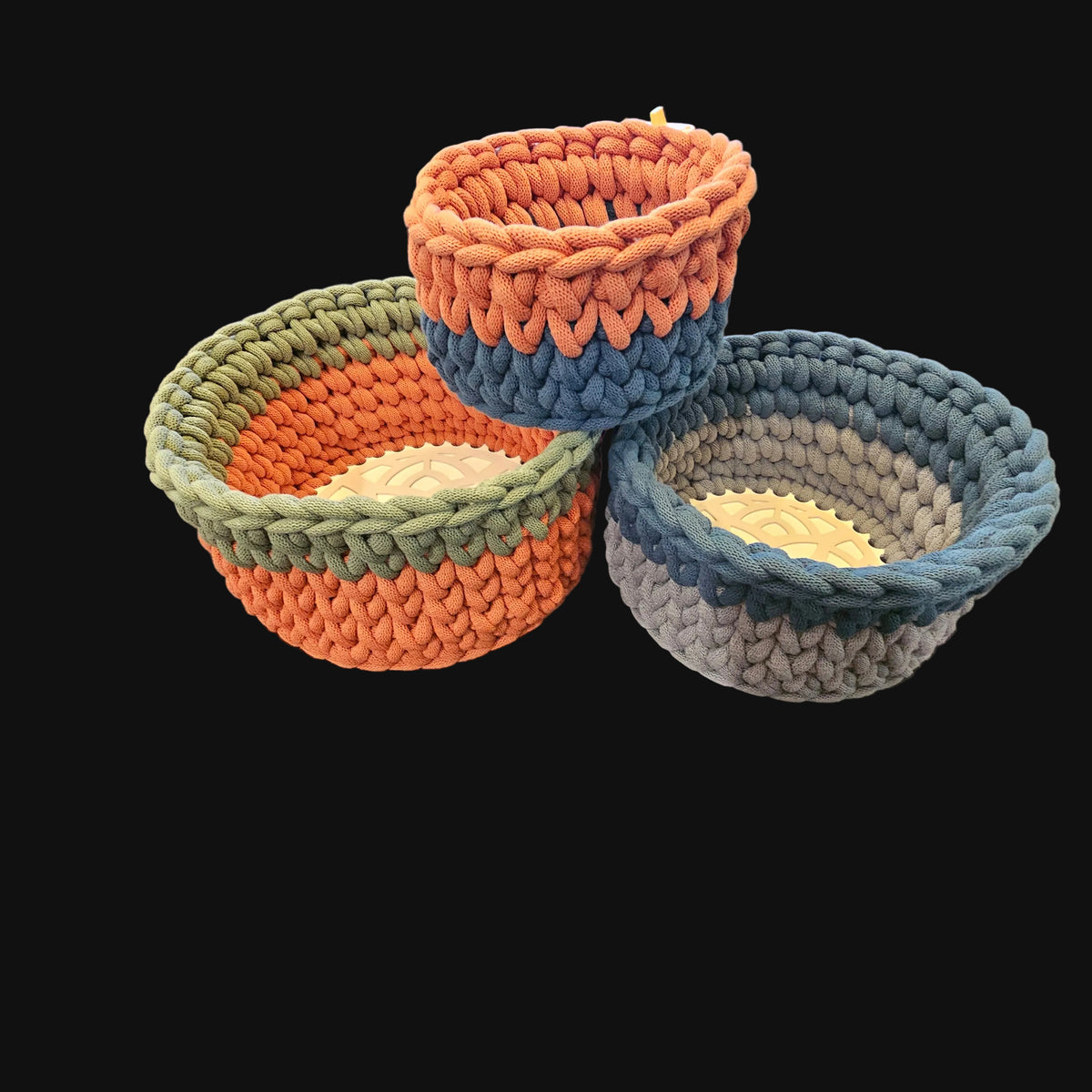 Three chunky crocheted storage baskets in concentric rings of olive green, slate blue, terracotta, and gray with a natural beige center Small 7x7x4; Medium 9x9x5; Large 12x12x6 overall
