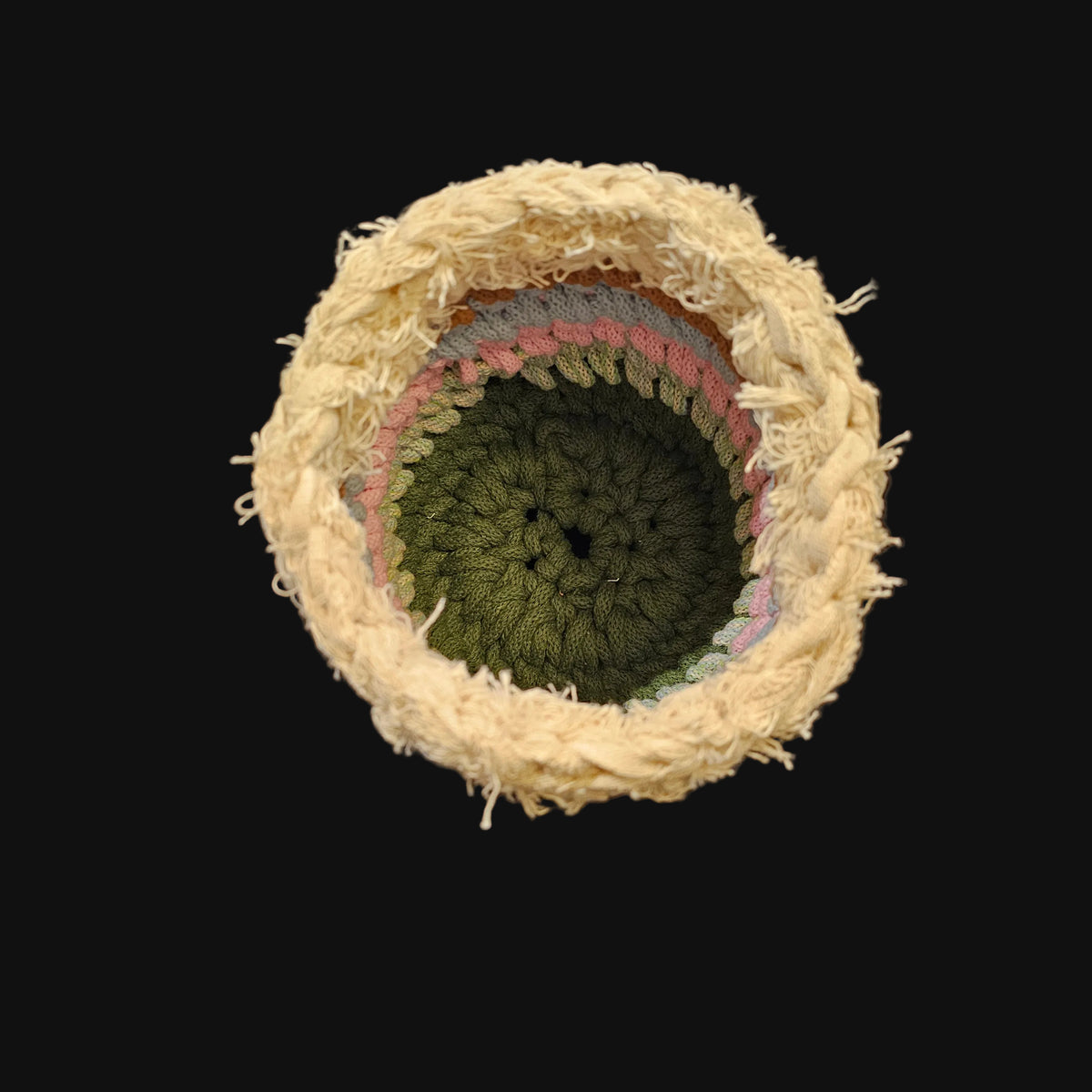 A handmade crocheted basket with a textured chevron pattern, featuring horizontal stripes of cream, brown, light blue, pink, sage green, and olive green, featuring a thick cream-colored frayed outer rim.  5x5x6 inches overall