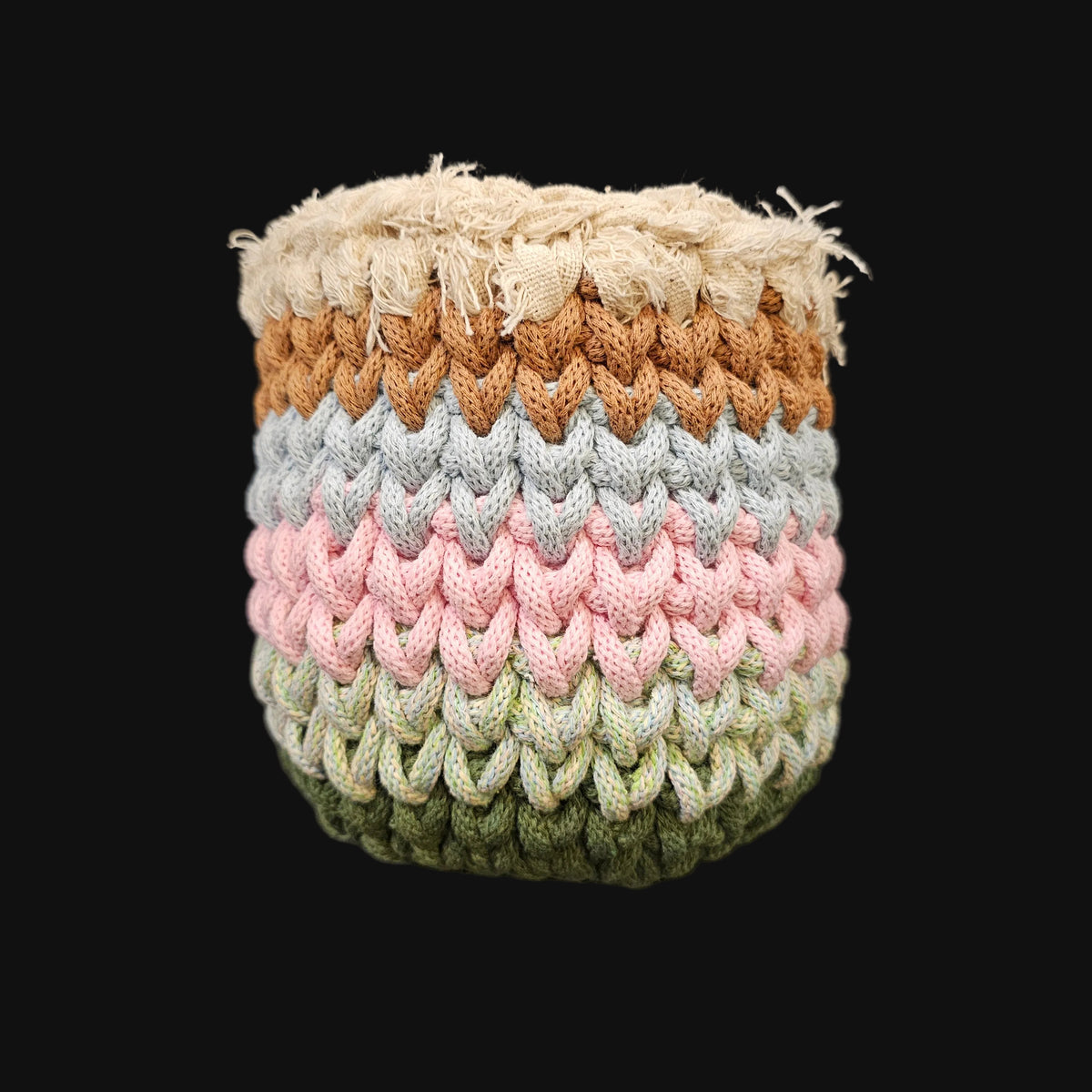 A handmade crocheted basket with a textured chevron pattern, featuring horizontal stripes of cream, brown, light blue, pink, sage green, and olive green, featuring a thick cream-colored frayed outer rim.  5x5x6 inches overall