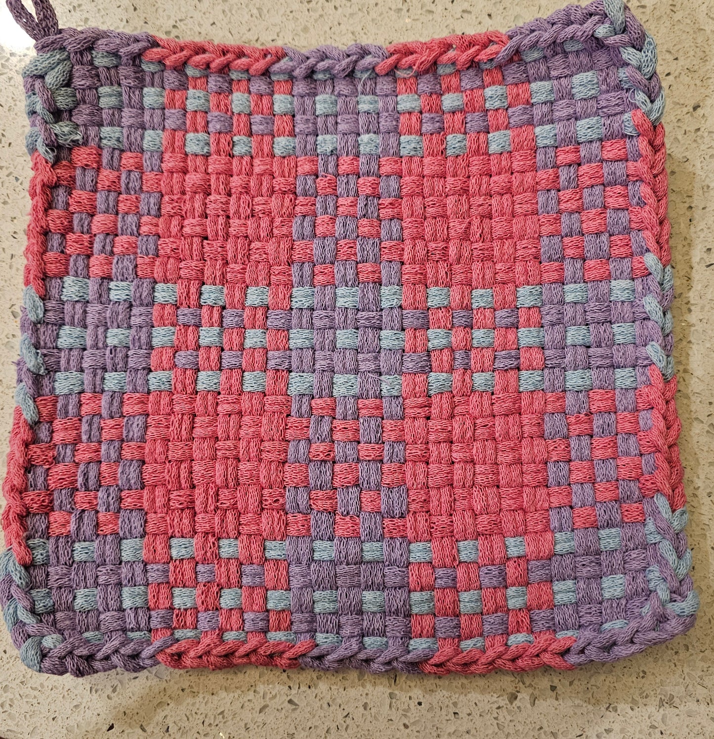 Woven potholder with a checkered pattern in pink and purple 