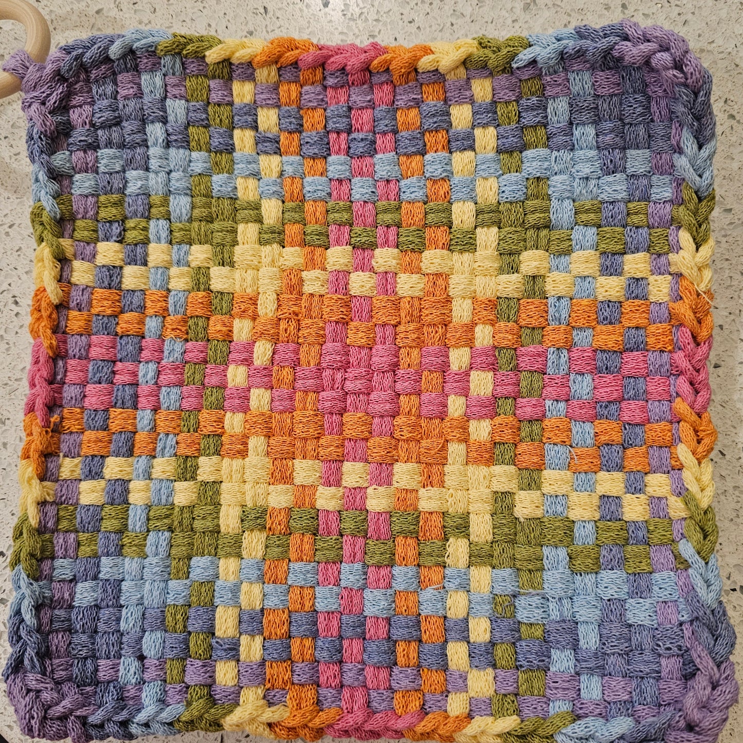 Multicolored potholder  in purples and yellows with a checkered pattern 