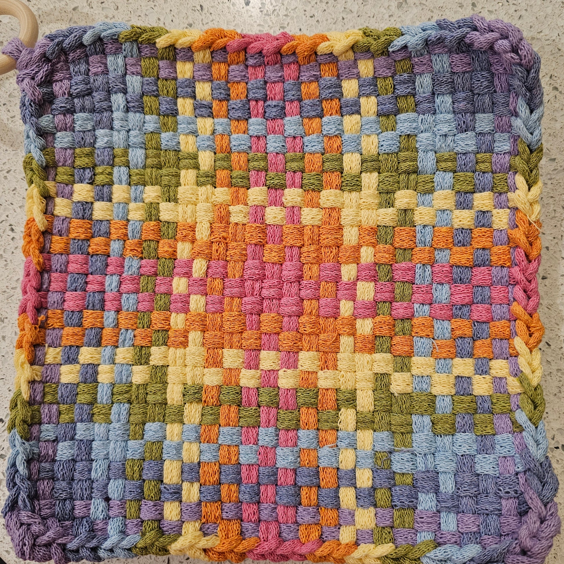 Multicolored potholder  in purples and yellows with a checkered pattern 