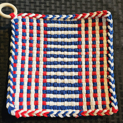 Woven trivet with red, white, and blue pattern on a black background