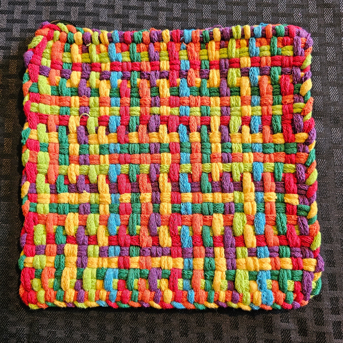 Multicolored woven fabric square on a dark textured background