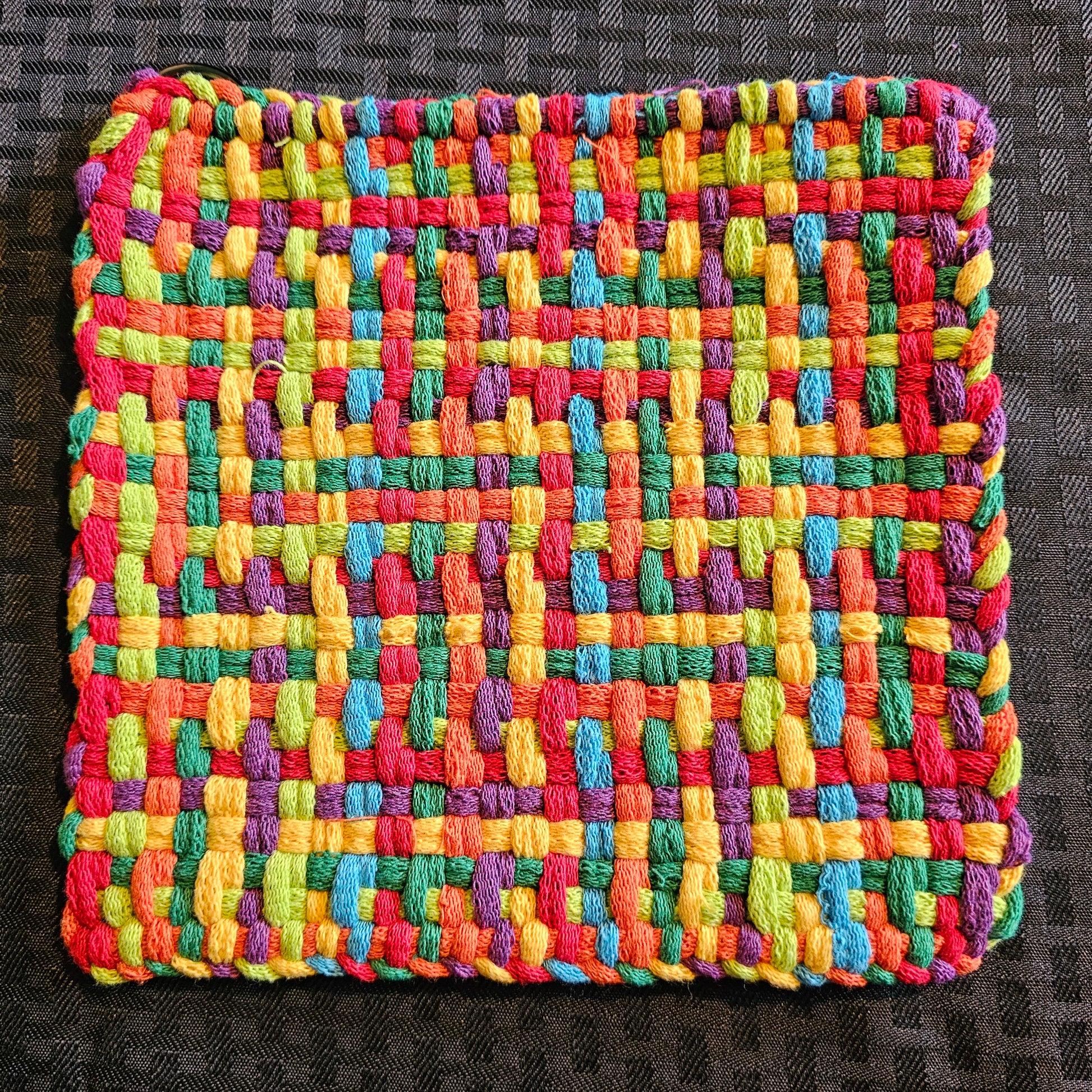 Multicolored woven fabric square on a dark textured background