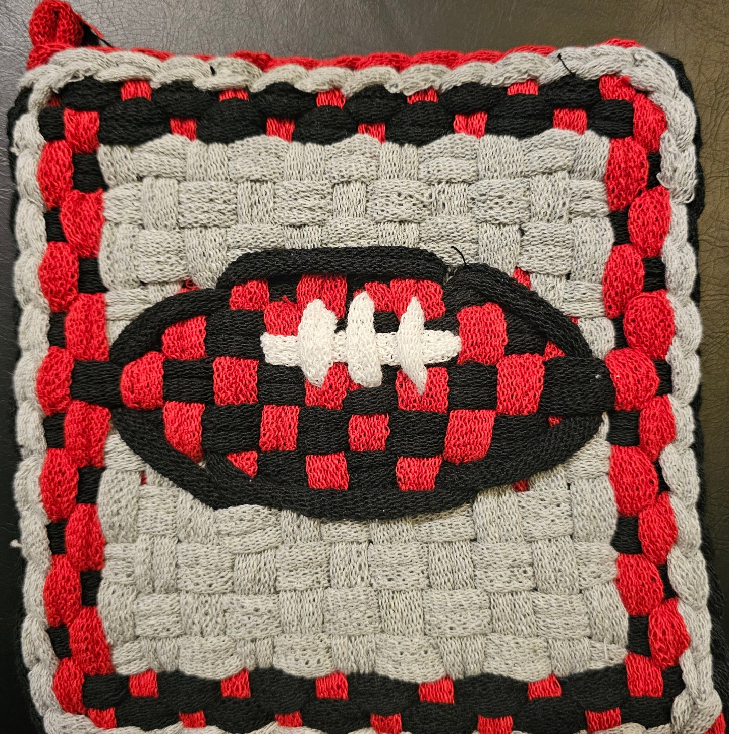 Woven rug with a football design in red, black, and white on a gray background