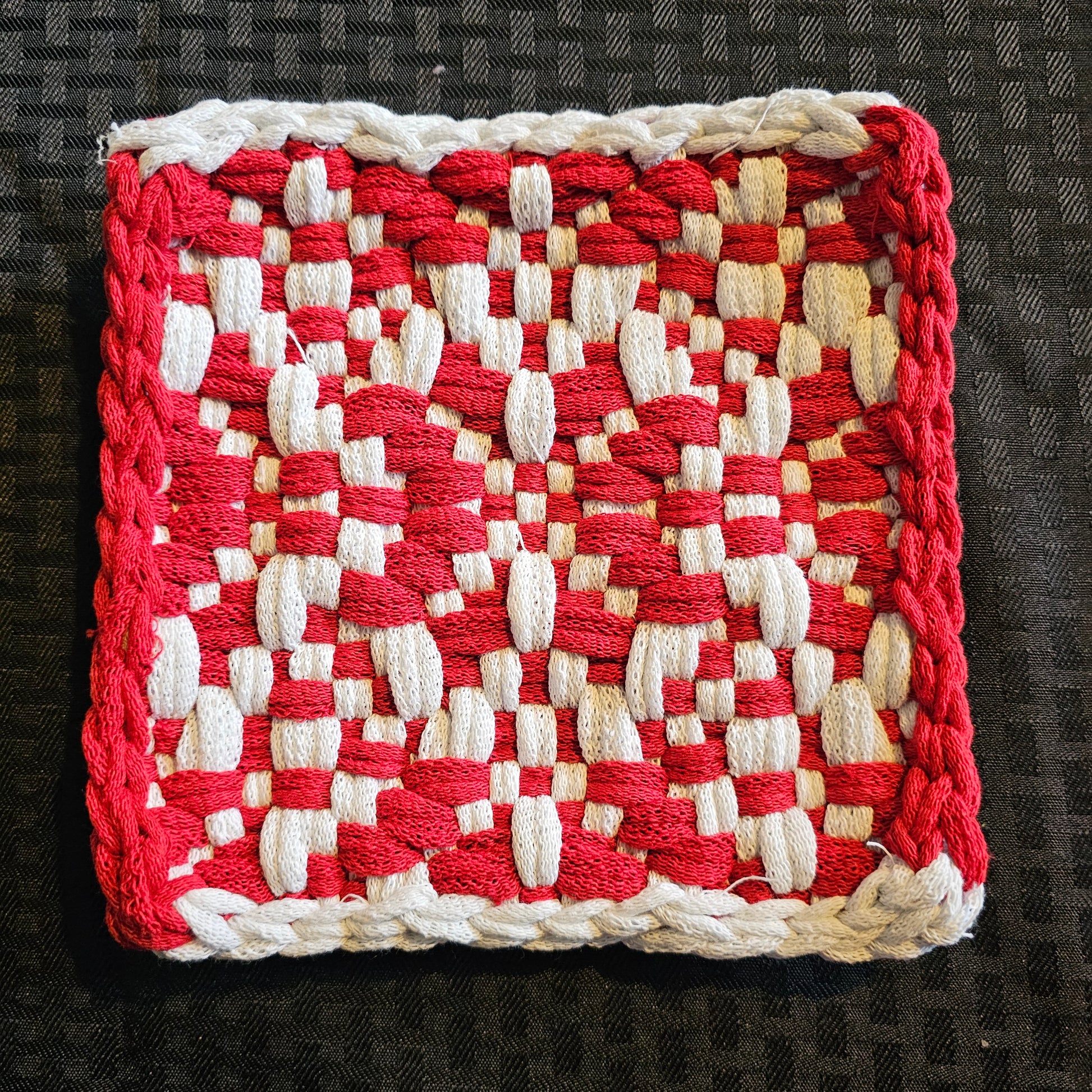 Red and white woven potholderron a dark textured background