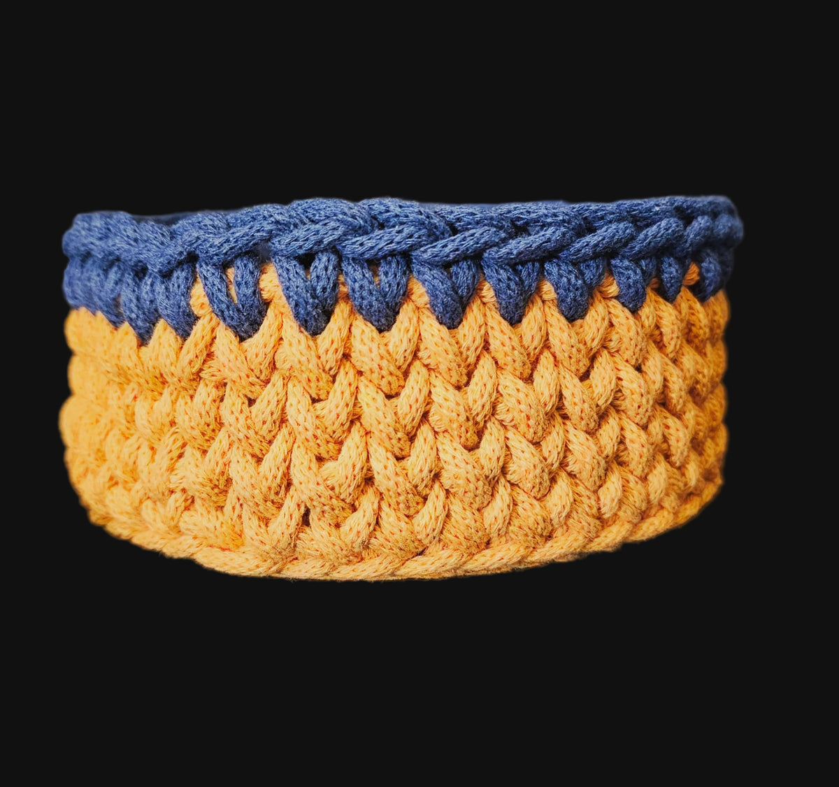 A round crocheted basket with an octopus design, featuring navy blue outer crochet trim, an orange middle band, and a dark blue center with a yellow-orange octopus and green seaweed pattern. 6x6x3 inches overall