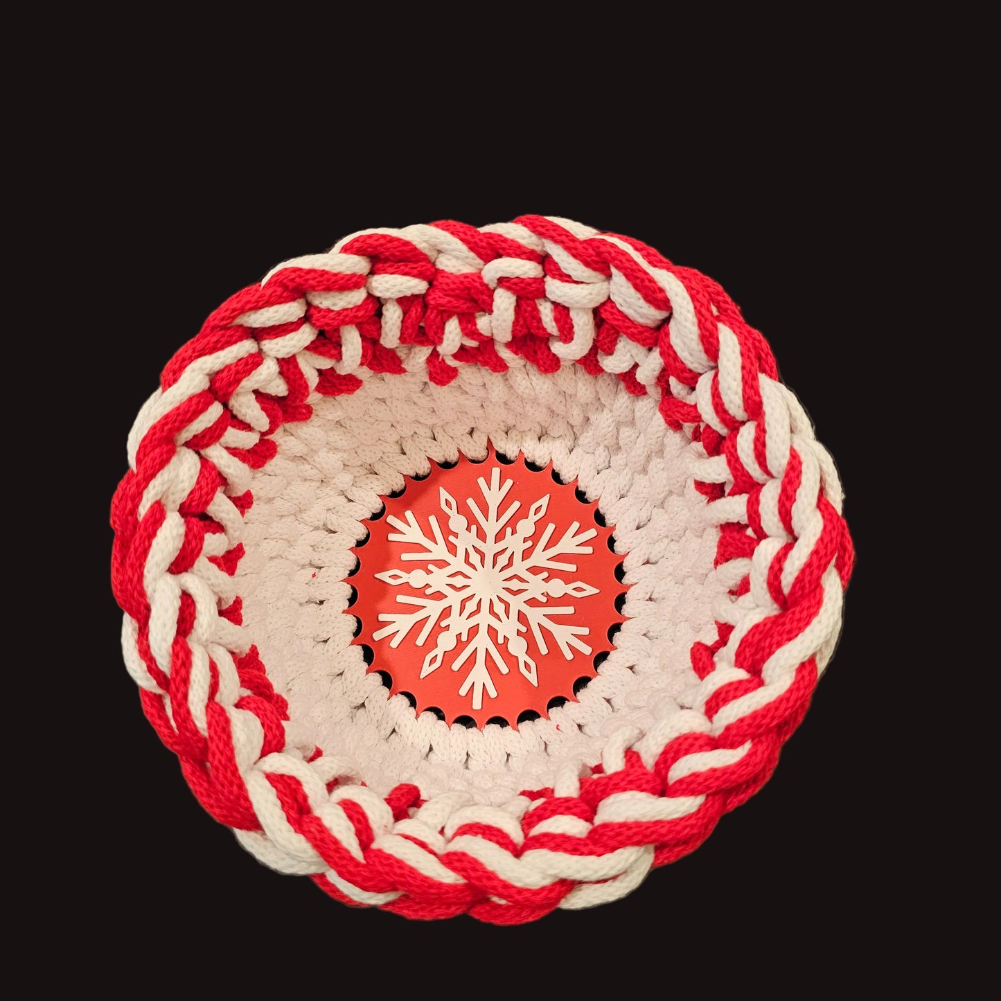 A round crocheted basket with a red and white outer border and a white snowflake design on a red base. 6x6x4 inches overall