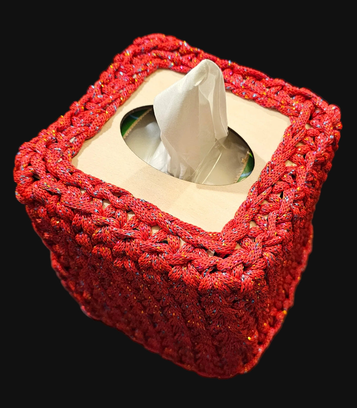 A square tissue box cover with a textured red braided crochet exterior and a beige interior. The cover has subtle multicolor glitter threads woven throughout. 5x5x6 inches overall