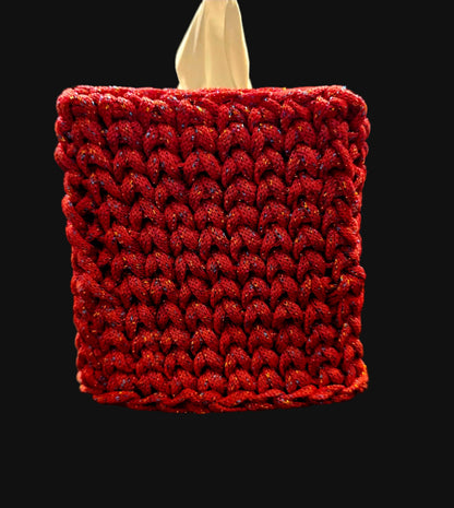 A square tissue box cover with a textured red braided crochet exterior and a beige interior. The cover has subtle multicolor glitter threads woven throughout. 5x5x6 inches overall
