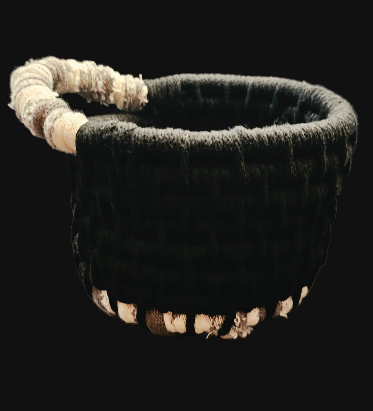 A handmade coiled basket with a black corded body and a beige, gray, and white striped handle made from sweatshirt fabric 6x7x5 inches overall including handle.