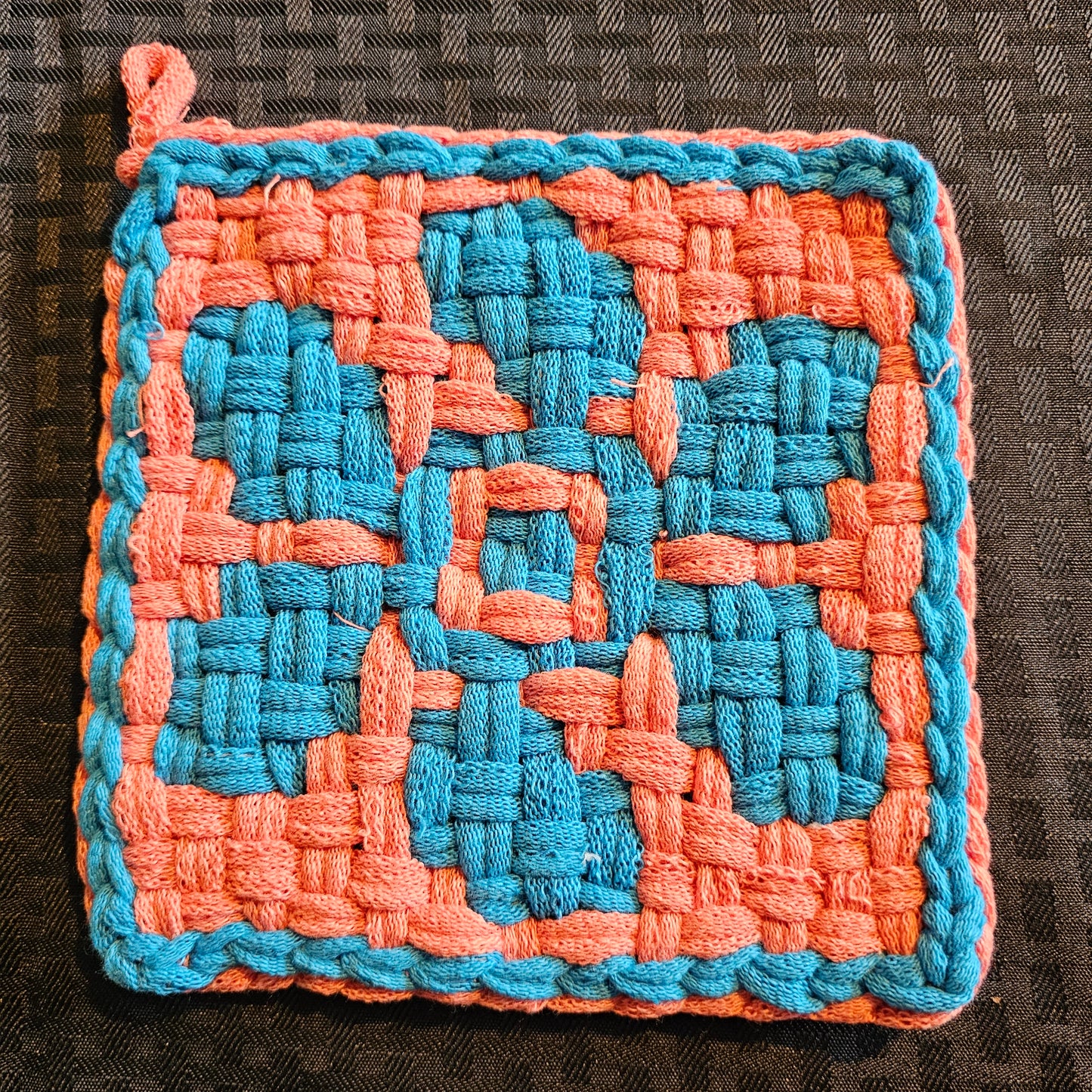 Woven square patch with blue and orange pattern on a textured surface