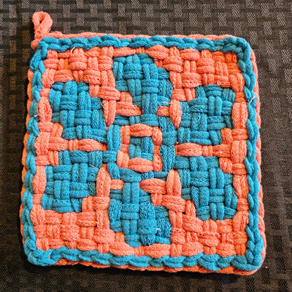 Woven square patch with blue and orange pattern on a textured surface