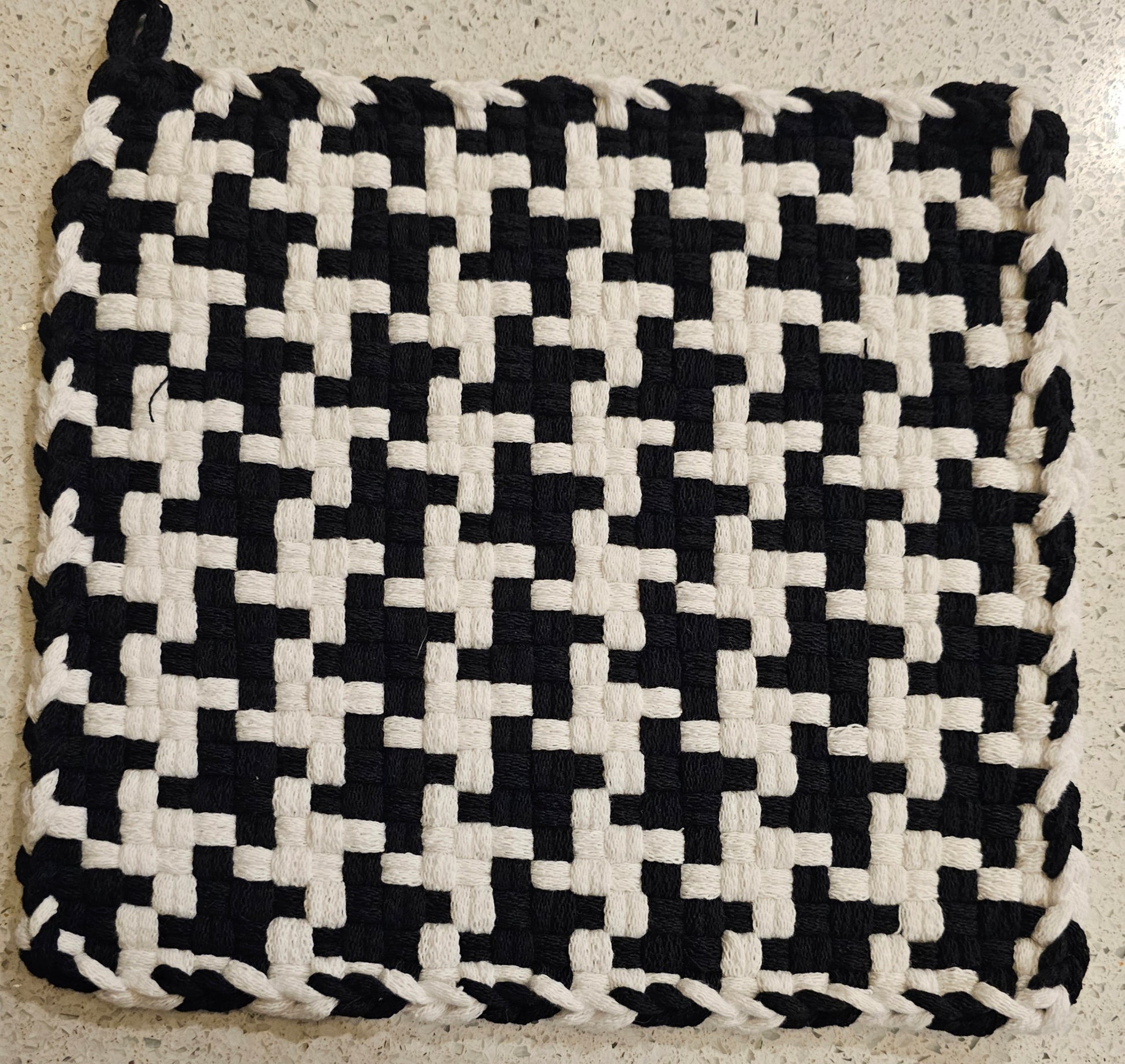 Black and white woven mat on a textured surface