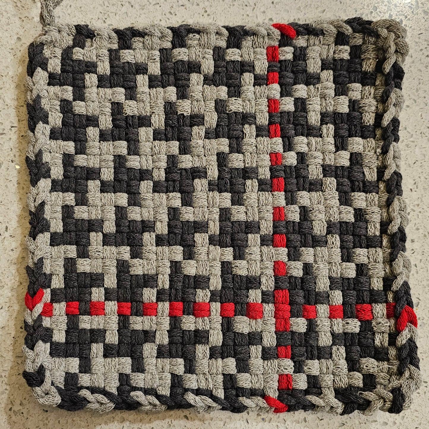 Woven potholder in shades of gray surface