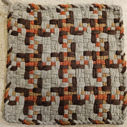 Woven potholder with a geometric pattern in earthy tones 